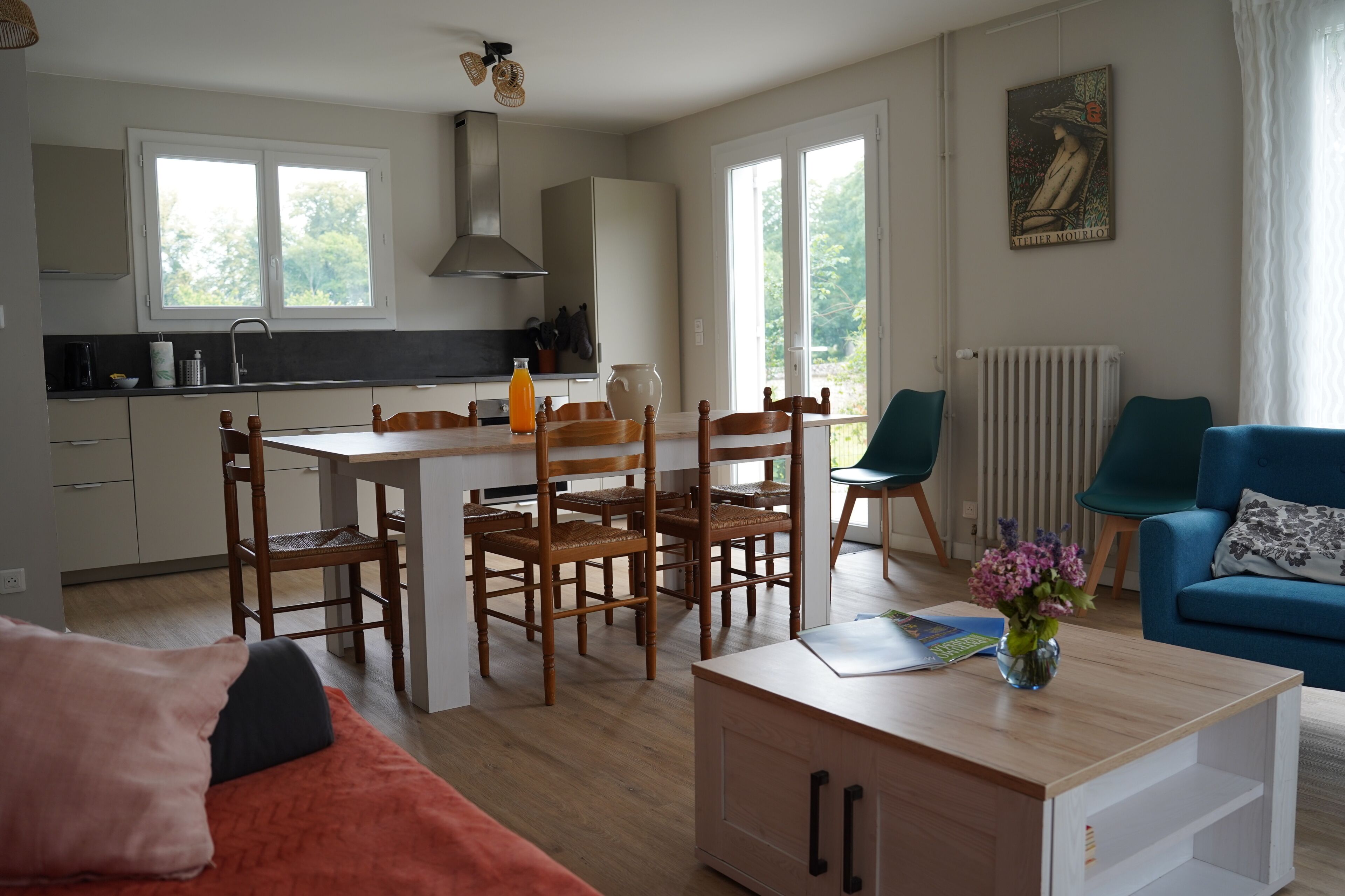 A modern living room with a dining table, chairs, a sofa, a coffee table, and a radiator.
