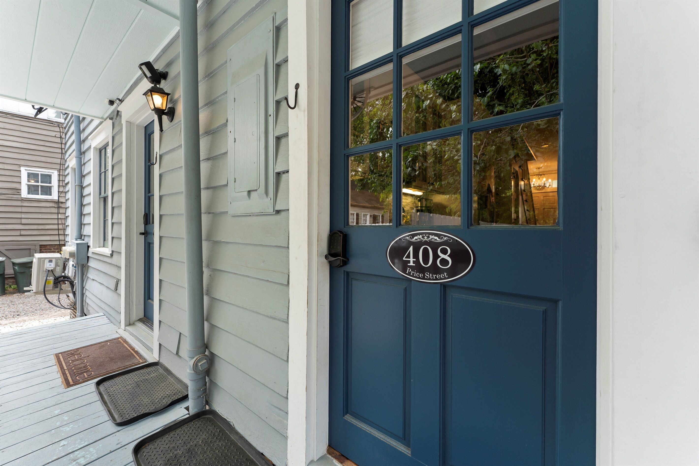 A blue door with a house number 408 on Price Street, a porch with a doormat, and a light fixture above the door.