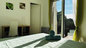 Ein Schlafzimmer mit einem Bett, einem Schreibtisch und einem Stuhl. Es gibt zwei Fenster mit Vorhängen.