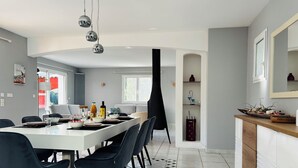 Ein moderner Essbereich mit einem weißen Tisch, schwarzen Stühlen und einer schwarzen Trennwand. Auf dem Tisch stehen Flaschen und Schalen, an der Wand hängt ein Spiegel.