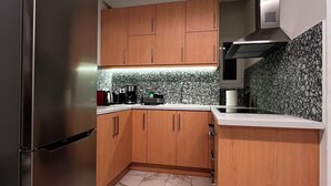 Eine kleine Küche mit Holzschränken, einem Edelstahlkühlschrank, einer Mikrowelle und einem Gasherd.
