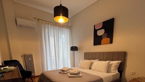 Ein Hotelzimmer mit Bett, Nachttisch, Lampe und einem Gemälde an der Wand.