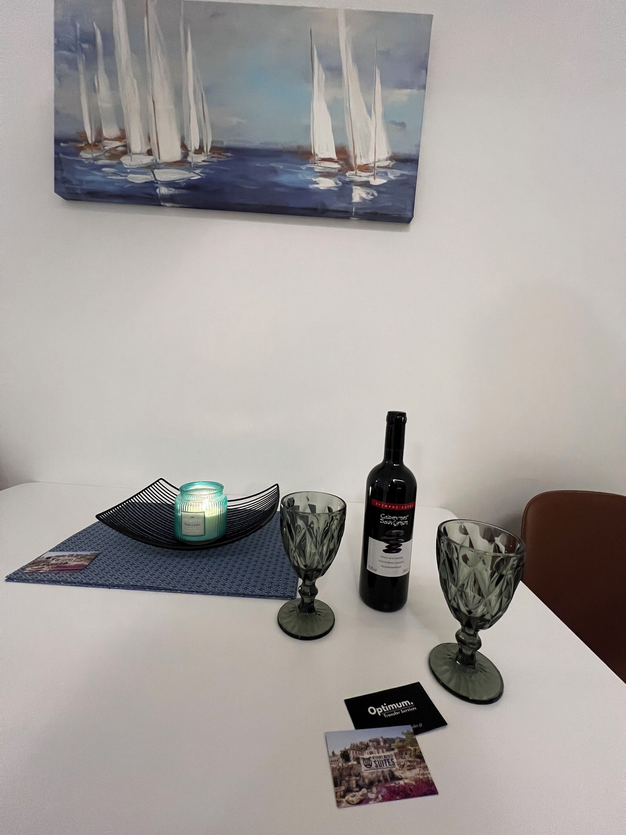 A table with a wine bottle, two glasses, a candle, and a brochure.