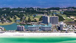 Un complexe hôtelier situé sur la côte, composé de plusieurs immeubles de grande hauteur, donnant sur la plage et entouré de verdure.