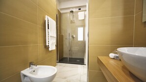 Une salle de bain moderne équipée d’un bidet, d’une douche et d’un grand lavabo.