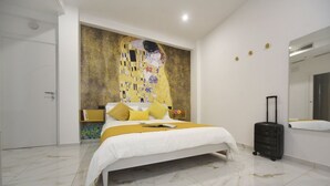 Une chambre à coucher moderne avec un grand lit, un tableau accroché au mur et une valise.