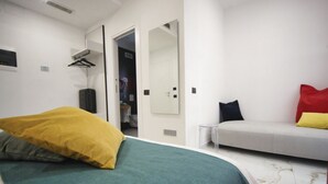 A bedroom with a bed, a sofa, a mirror, and a door leading to a bathroom. - Becoloured Circles Suite. Where it is possible to dream among the masterpieces of art. (Napoli)