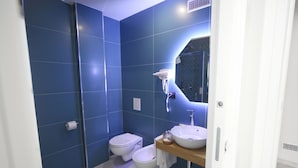 A modern bathroom with blue walls, a white toilet, a bidet, and a vanity with a mirror and sink. - Becoloured Wave Suite. Where it is possible to dream among the masterpieces of art. (Napoli)