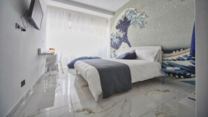 A modern bedroom with a large bed, a mounted TV, and a wall mural. - Becoloured Wave Suite. Where it is possible to dream among the masterpieces of art. (Napoli)