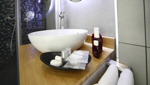 Une salle de bain moderne avec un grand lavabo blanc, un miroir et des articles de toilette posés sur le comptoir.