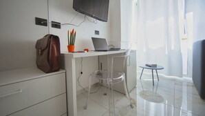 Une chambre moderne équipée d’un bureau, d’un ordinateur portable et d’un téléviseur fixé au mur.