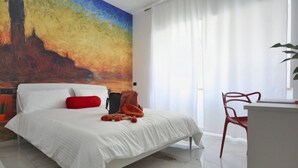A modern hotel room with a large bed, a desk, and a painting on the wall. - Venice Suite. Becoloured, where it is possible to dream among art masterpieces. (Napoli)