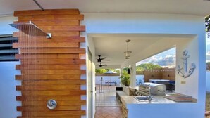 Un espace cuisine extérieur moderne, doté d’un barbecue encastré, d’un évier et d’un ventilateur de plafond.