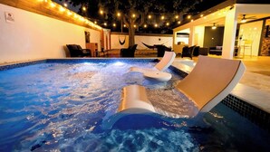 Une piscine extérieure chauffée, dotée de chaises longues, de guirlandes lumineuses et d’une architecture moderne.
