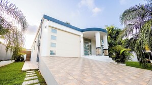 Une maison moderne avec un toit incurvé, un allée couverte et une pelouse bien entretenue.
