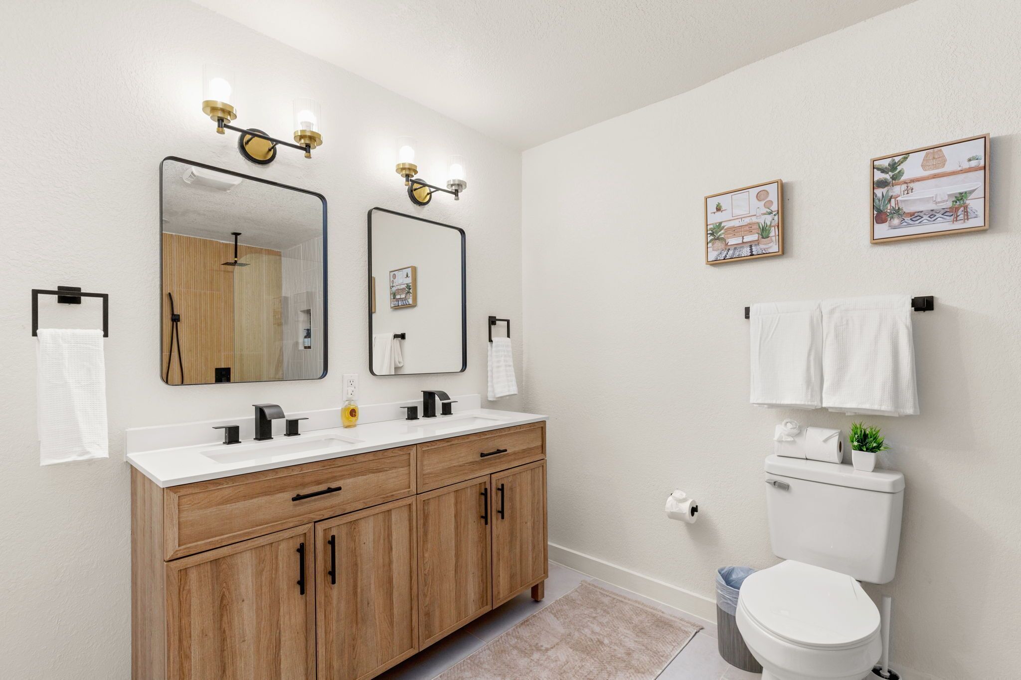A modern bathroom with a wooden vanity, two mirrors, and a toilet.
