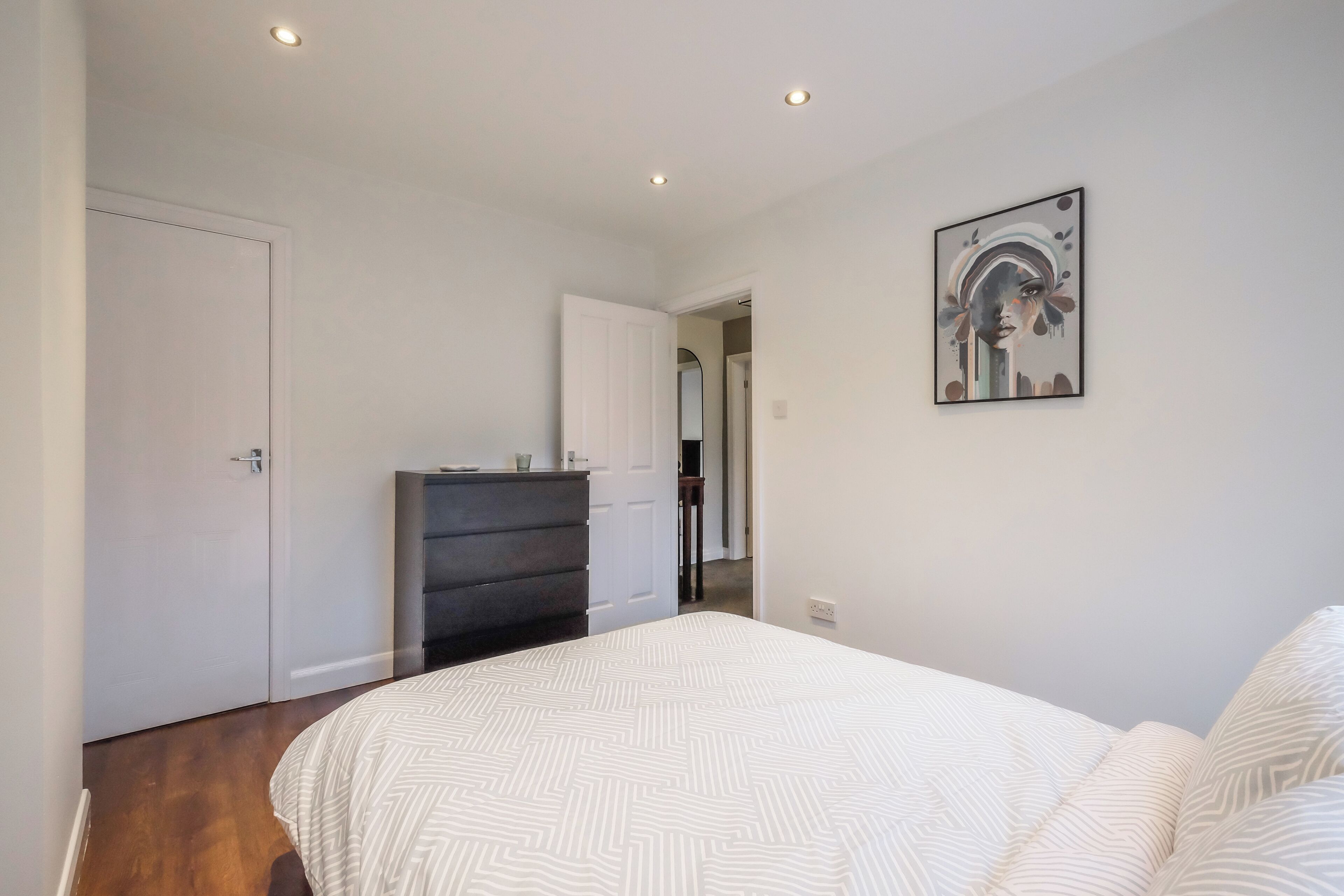 A bedroom with a bed, a dresser, and a door.