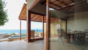 A modern villa with a dining area, a pool, and a view of the ocean. - Casa Kahu by Wynwood House (Los Organos)