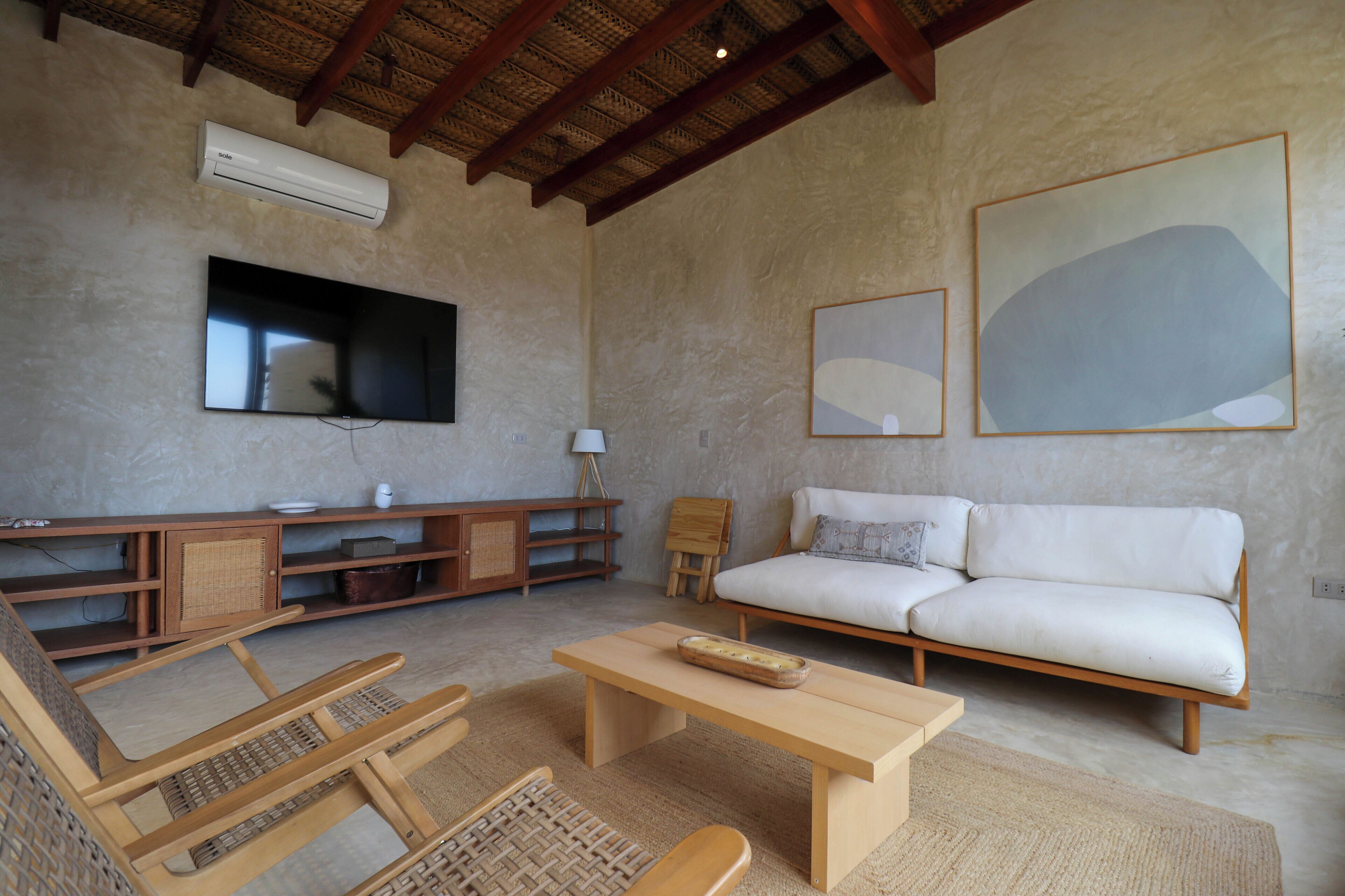 Una sala de estar con sofá, mesa de centro, televisor y un mueble de madera.