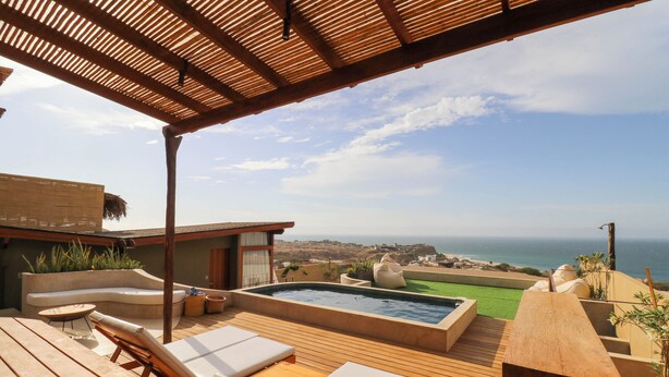 A wooden deck with lounge chairs and a hot tub overlooking a coastal landscape. - Casa Kahu by Wynwood House (Los Organos)