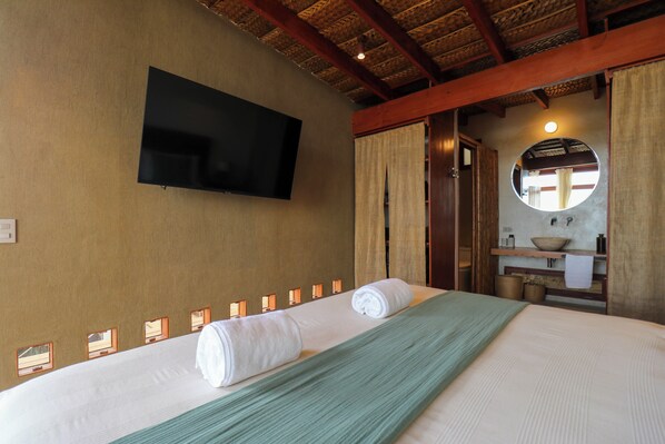 A hotel room with a bed, a flat-screen TV, a mirror, and a small bathroom area. - Casa Kahu by Wynwood House (Los Organos)