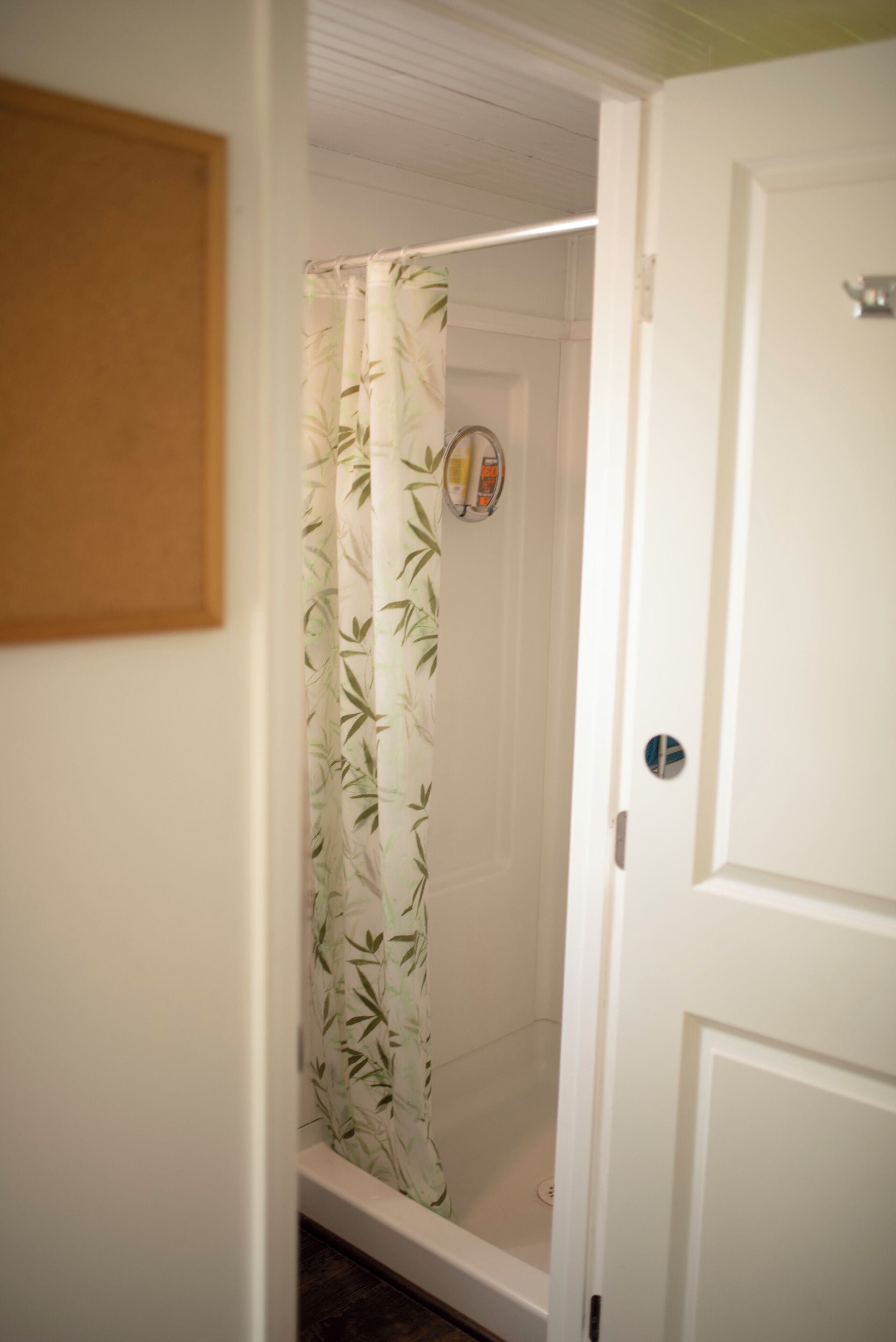 A bathroom with a bamboo shower curtain, a white door, and a visible towel rack.