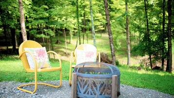 Two yellow chairs with floral cushions in a forest setting.