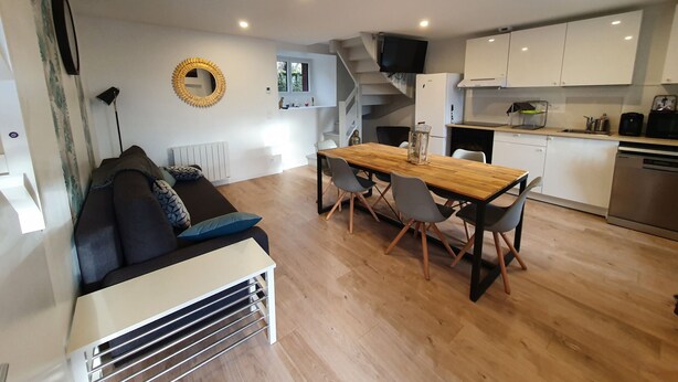 A modern kitchen with white cabinets, a wooden dining table, and a built-in stove.