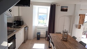 A compact kitchen with a wooden table and chairs, a window with a view, and a radiator.