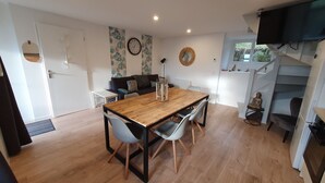 A modern kitchen with a wooden dining table, grey chairs, and a staircase with a Buddha statue.