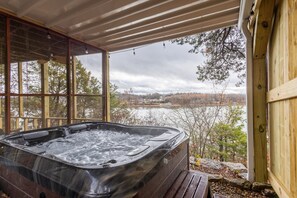 A hot tub in a covered outdoor area with a view of a lake and trees. - Charming Cottage-Romantic-Table Rock Lake Views-Silver Dollar City-Hot Tub-WiFi (Shell Knob)