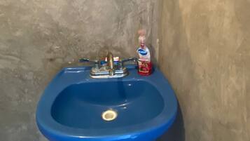 Een badkamer met een blauwe wasbak, een spiegel en een fles vloeibare zeep.