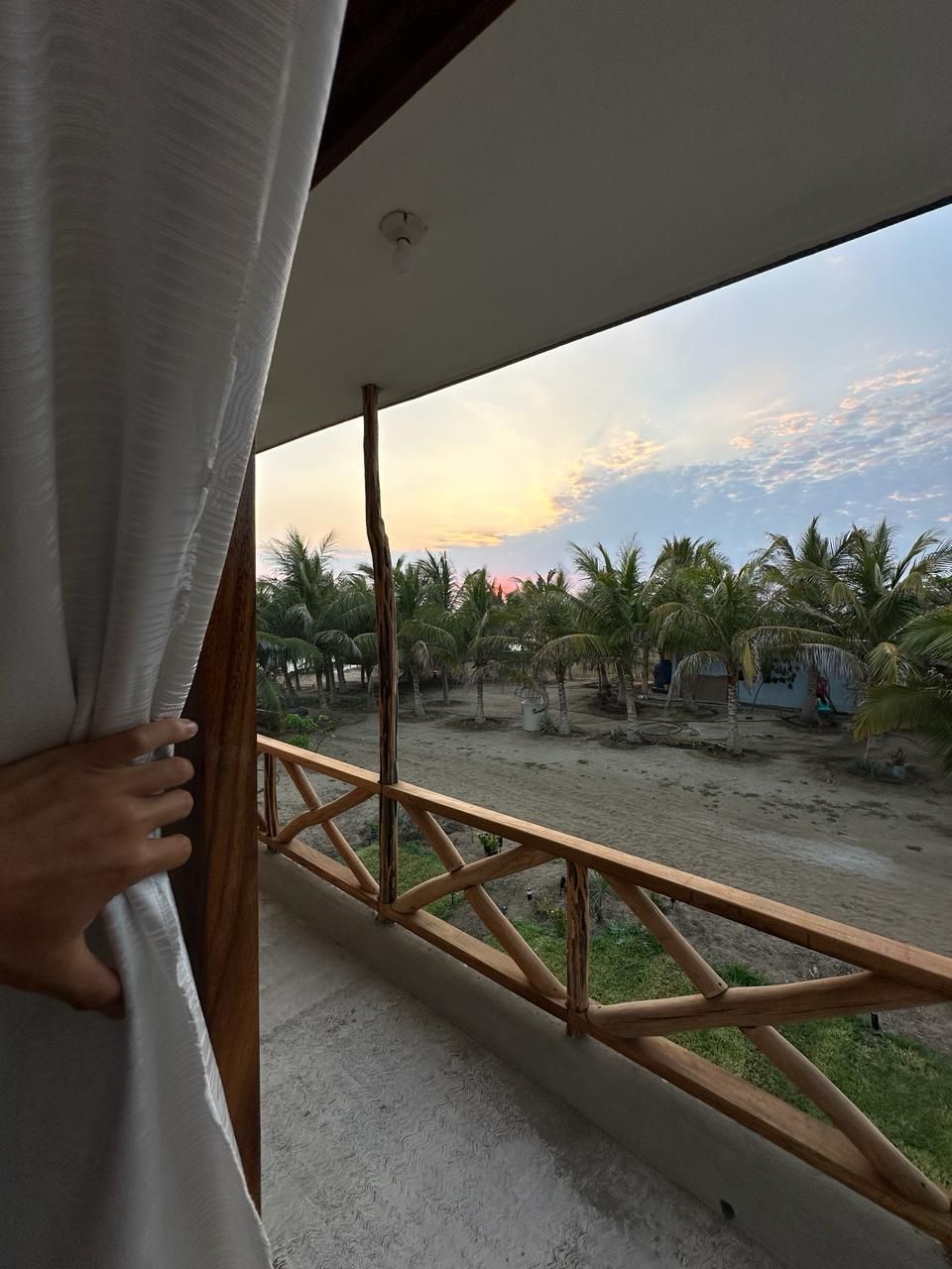 Ein Balkon mit Blick auf Palmen und einen Sonnenuntergang.