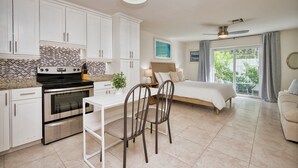 A modern kitchen with white cabinets, a built-in oven, and a dining area with two chairs.
