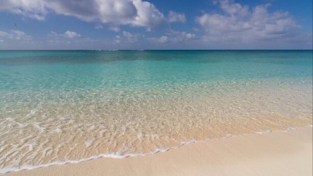 A beach with clear turquoise water and a sandy shore.