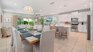 A modern kitchen with white cabinets, a stainless steel refrigerator, and a built-in oven. - Ohana Dream 6 bedrooms, 5 bathroom, private pool, 10 mins from Disney!  (Kissimmee)