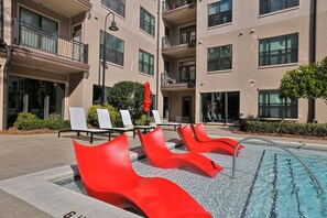 A pool area with red lounge chairs and a clear pool. - Ebony Ivory Midtown King Bed (Atlanta)
