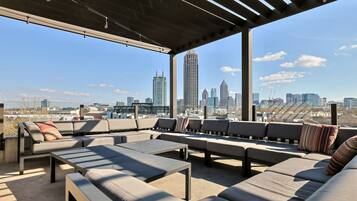 Un espace extérieur aménagé avec plusieurs canapés et tables, offrant une vue sur le panorama urbain.