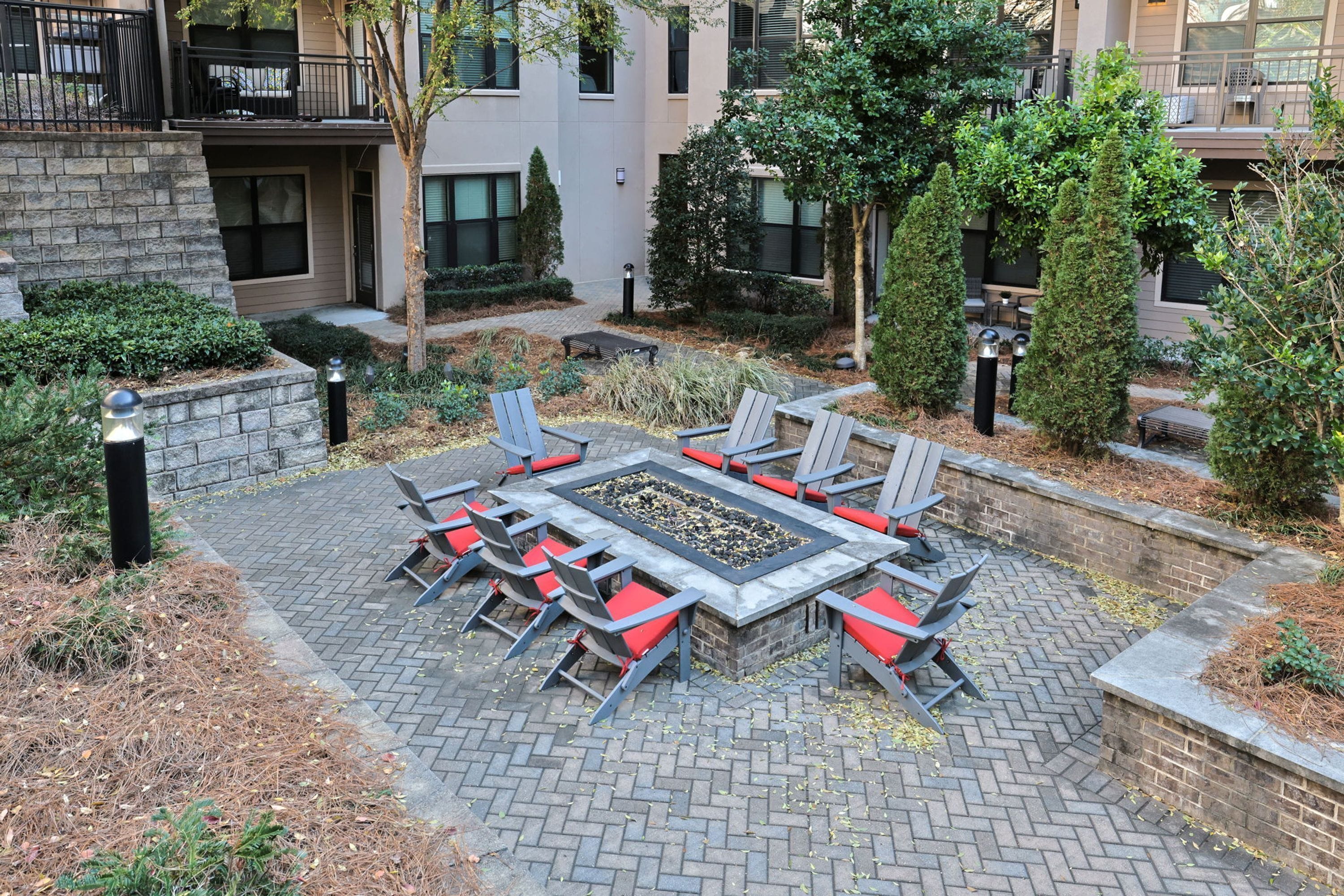 Ein Innenhof mit Feuerstelle, Sitzgelegenheiten im Freien und umlaufendem Grün.