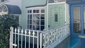 A two-story house with a green door, white-framed windows, and a white picket fence. - North Laine Sunny Cottage with parking (Brighton and Hove)