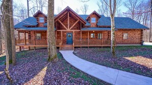A log cabin with a porch, a front door, and a pathway leading to the entrance. - Treehouse Lodge: Luxury Log Cabin Retreat in Hocking Hills (Laurelville)