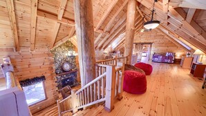 A wooden cabin with a loft bedroom, a stone fireplace, and a staircase. - Treehouse Lodge: Luxury Log Cabin Retreat in Hocking Hills (Laurelville)