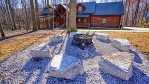 A log cabin with a porch and a fire pit surrounded by rocks. - Treehouse Lodge: Luxury Log Cabin Retreat in Hocking Hills (Laurelville)