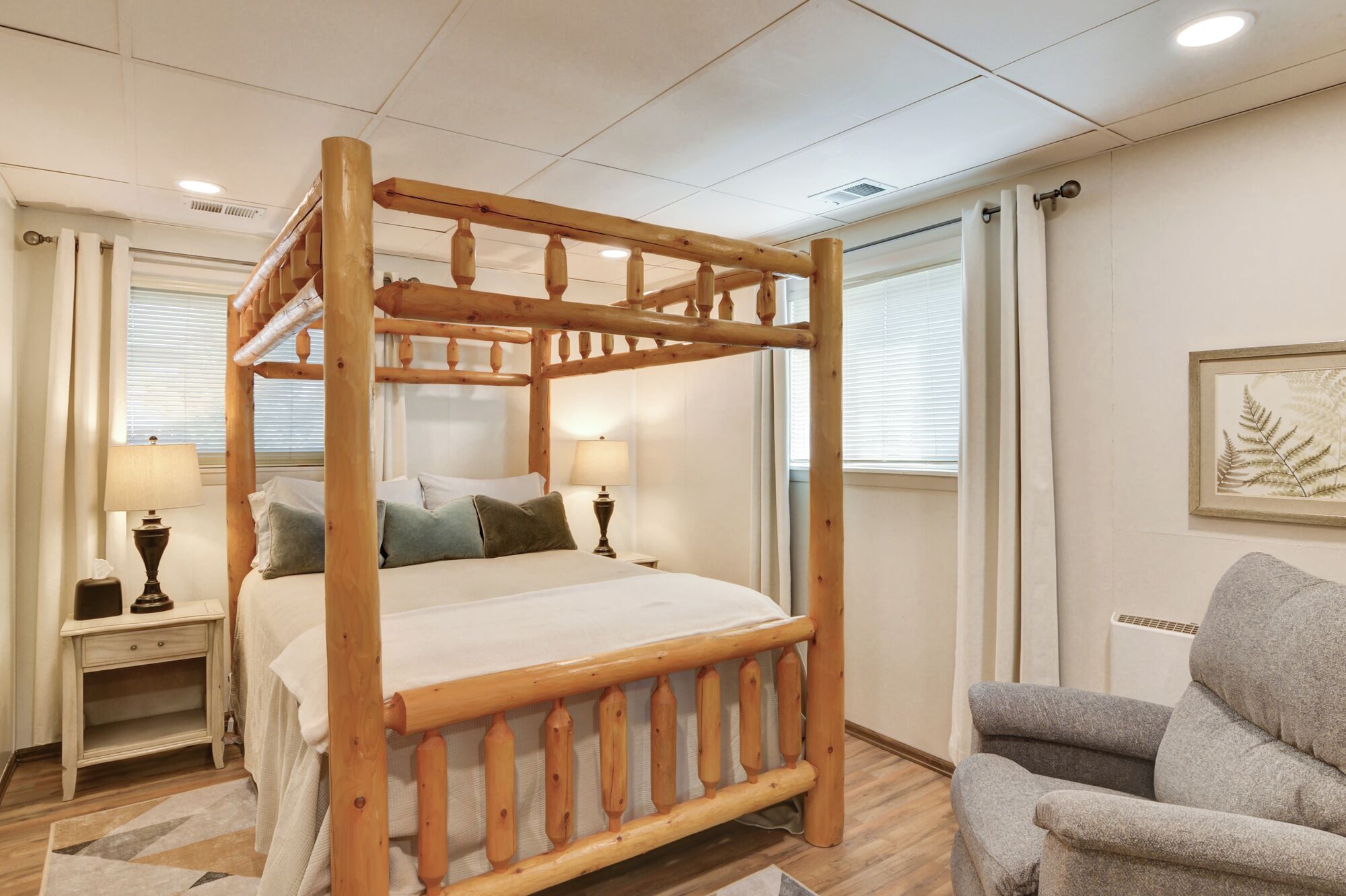 Un lit à baldaquin avec un cadre en bois, une table de chevet avec une lampe et une chaise dans une chambre d’hôtel.