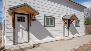 A single-story house with a front door, two windows, and a small porch area.