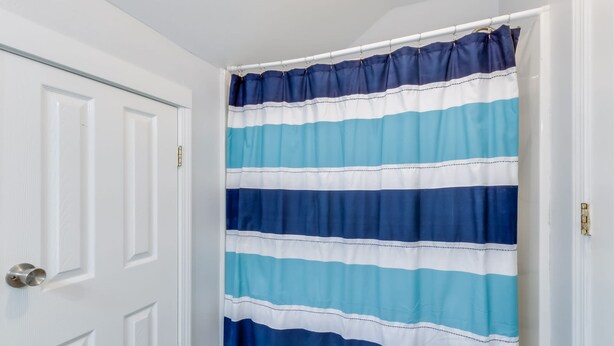 A bathroom with a striped shower curtain. - Sel De Vie 6 BR Sleeps 18 dog Friendly (Gulf Shores)