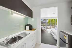 A modern kitchen with a sink, a coffee machine, and a refrigerator. - Bay View Motel - California Beach (Lorne)