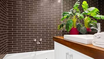 Een badkamer met een badkuip, een witte wastafel en twee potten met planten.