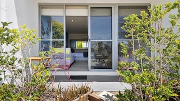 A modern house with large sliding glass doors leading to a bedroom with a bed and a chair.