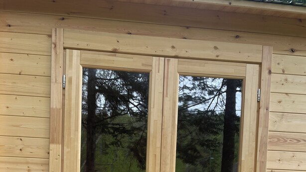 Una puerta doble de madera con un panel de vidrio, un tirador de metal y un adorno metálico negro en el suelo.